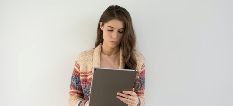 A woman holding a tablet, looking for online therapy for anxiety solutions.